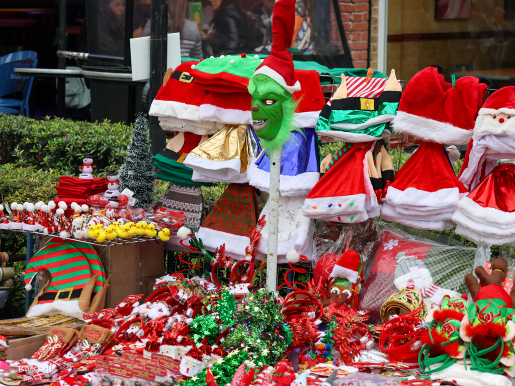 A vibrant street market in Mexico displays festive Christmas merchandise, blending global influences like Santa hats with distinctly Mexican traditions. Unlike in the U.S., where Christmas decorations focus on trees and lights, Mexican Christmas often centers around nativity scenes, piñatas, and local holiday crafts.