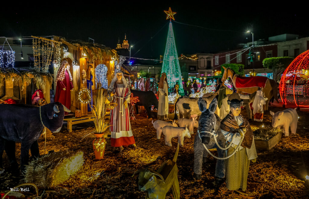 An illuminated nativity scene in a public plaza captures the heart of Mexican Christmas traditions, blending religious devotion with festive lights and local craftsmanship
