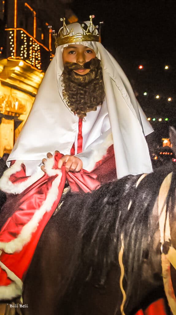A young participant dressed as one of the Three Wise Men rides through the streets during a lively Three Kings Day celebration in Mexico. While Santa Claus dominates Christmas traditions in the United States, Mexican Christmas extends to January 6th, with the Three Kings bringing gifts to children, honoring the journey of the Magi.